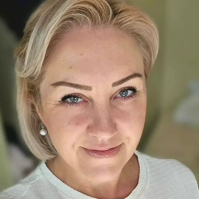 Elizabeth Holland, close-up portrait, smiling softly in a light top