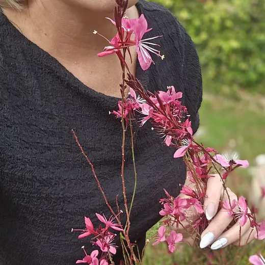 Elizabeth's hands holding delicate pink wildflowers